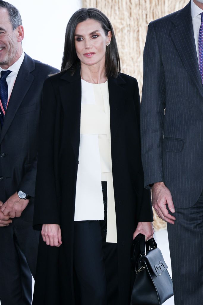 Letizia com blusa branca e casaco preto
