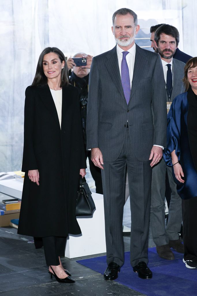 Rainha Letizia com casaco preto chique ao lado de Felipe
