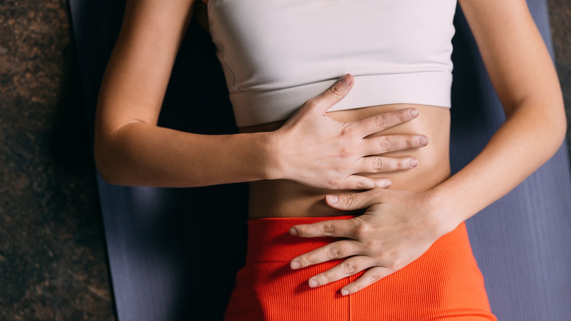 Tranquil Bliss: Anonymous Woman Lying on Yoga Mat, Hands on Belly in Relaxation