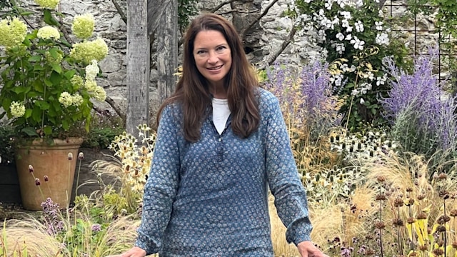 Rachel de Thame in a blue jacket behind a wooden rail