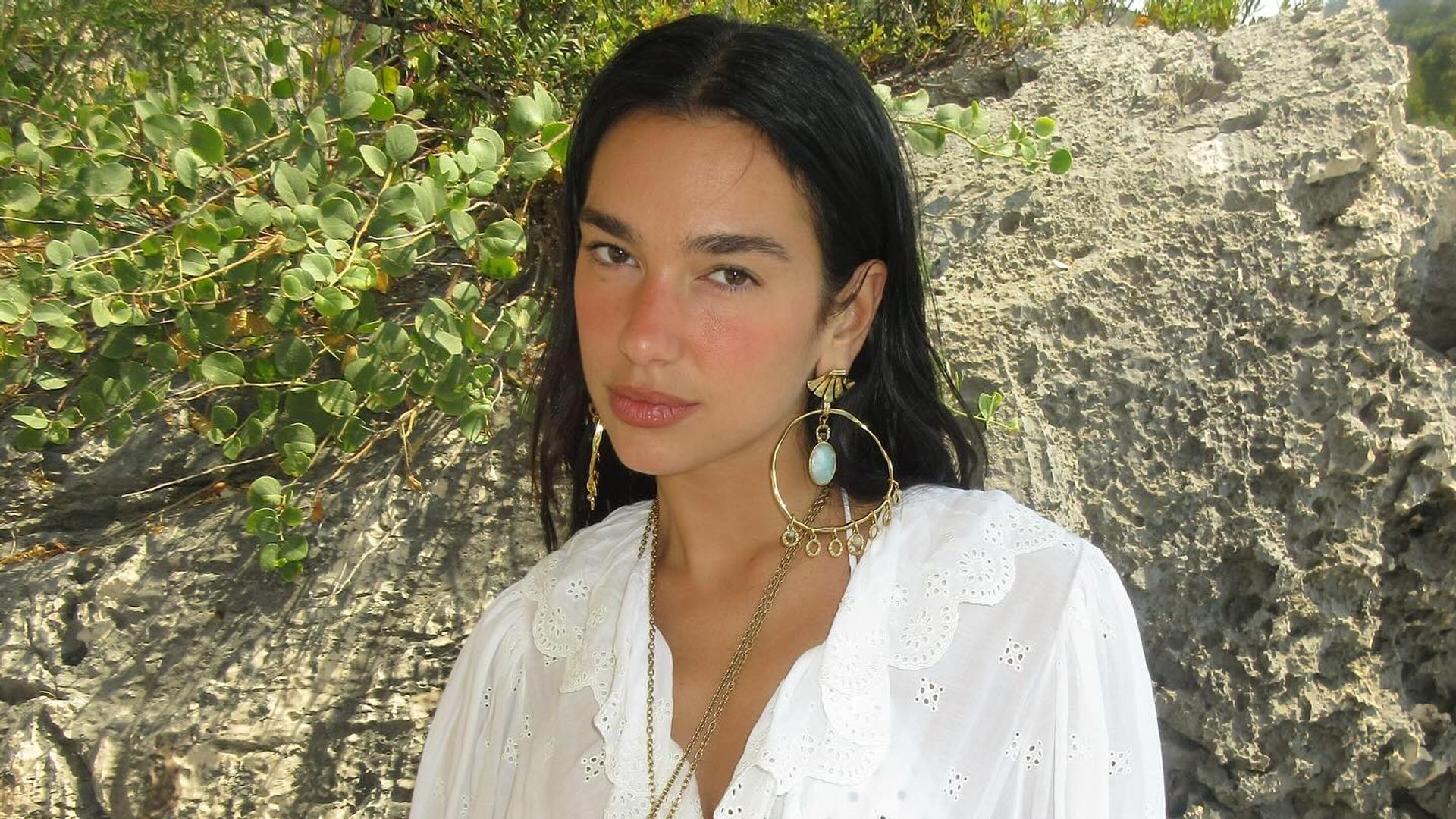 Dua Lipa poses in a white blouse and bikini bottoms