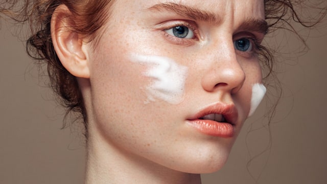 Portrait of a young woman who's applies skin cream