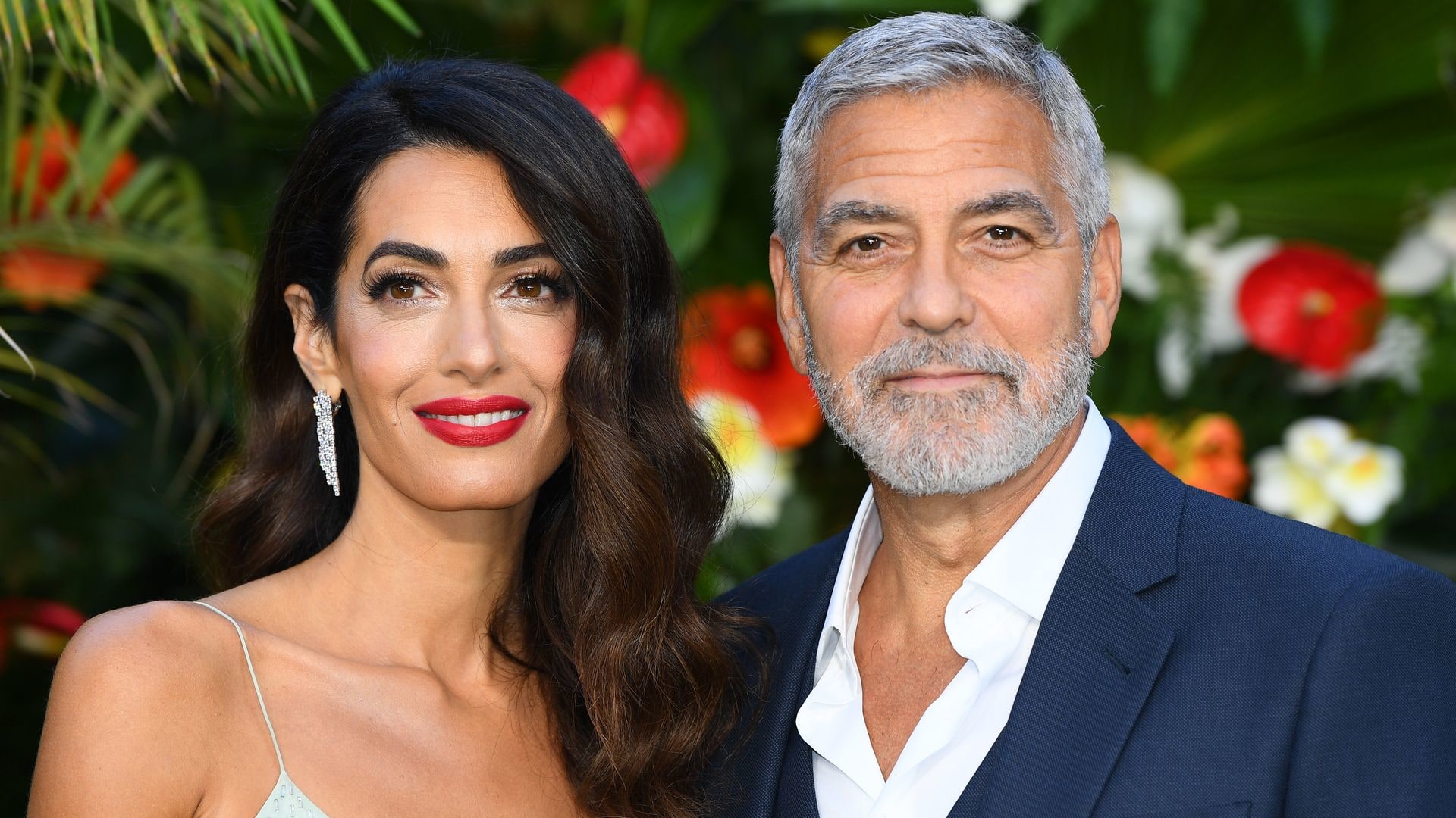 George and Amal Clooney against leafy backdrop