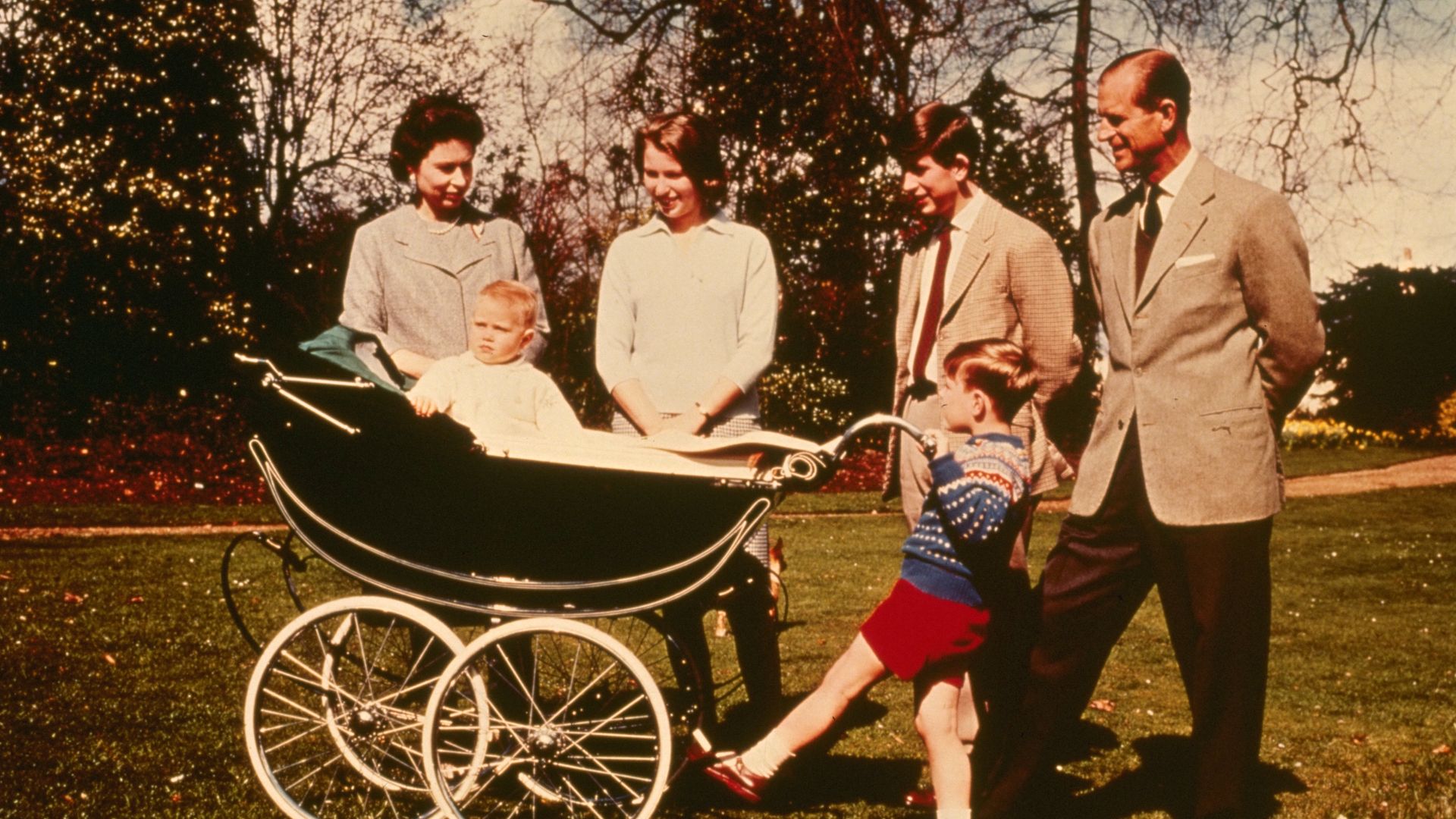 The Queen, Princess Anne, Prince Charles, Prince Philip and Prince Andrew looking at a baby Prince Edward in a pram