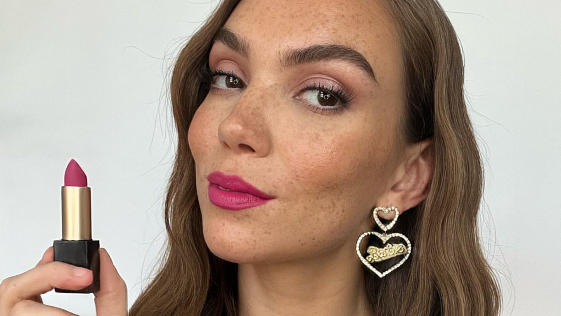 Makeup artist yasmin salmon holds a pink lipstick for a barbie inspired beauty look