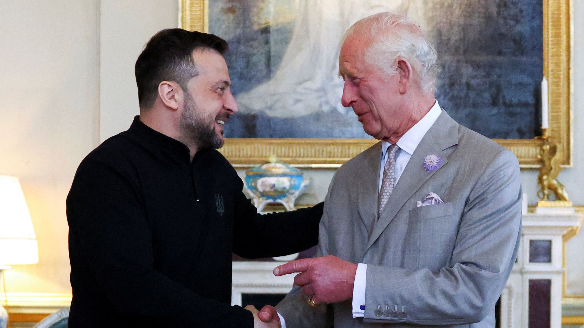 President Volodymyr Zelensky shaking hands with King Charles; the duo are smiling