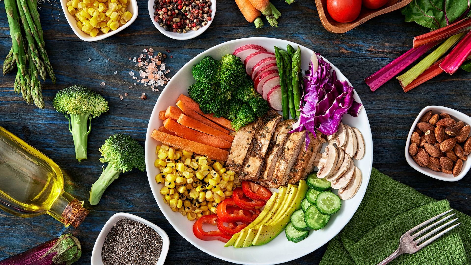 Healthy eating and diet concepts. Colorful spring salad on rustic white wood table. Included ingredients: Chicken, tomatoes, broccoli, lettuce, bell peppers, mushroom, carrots, radicchio, almonds.