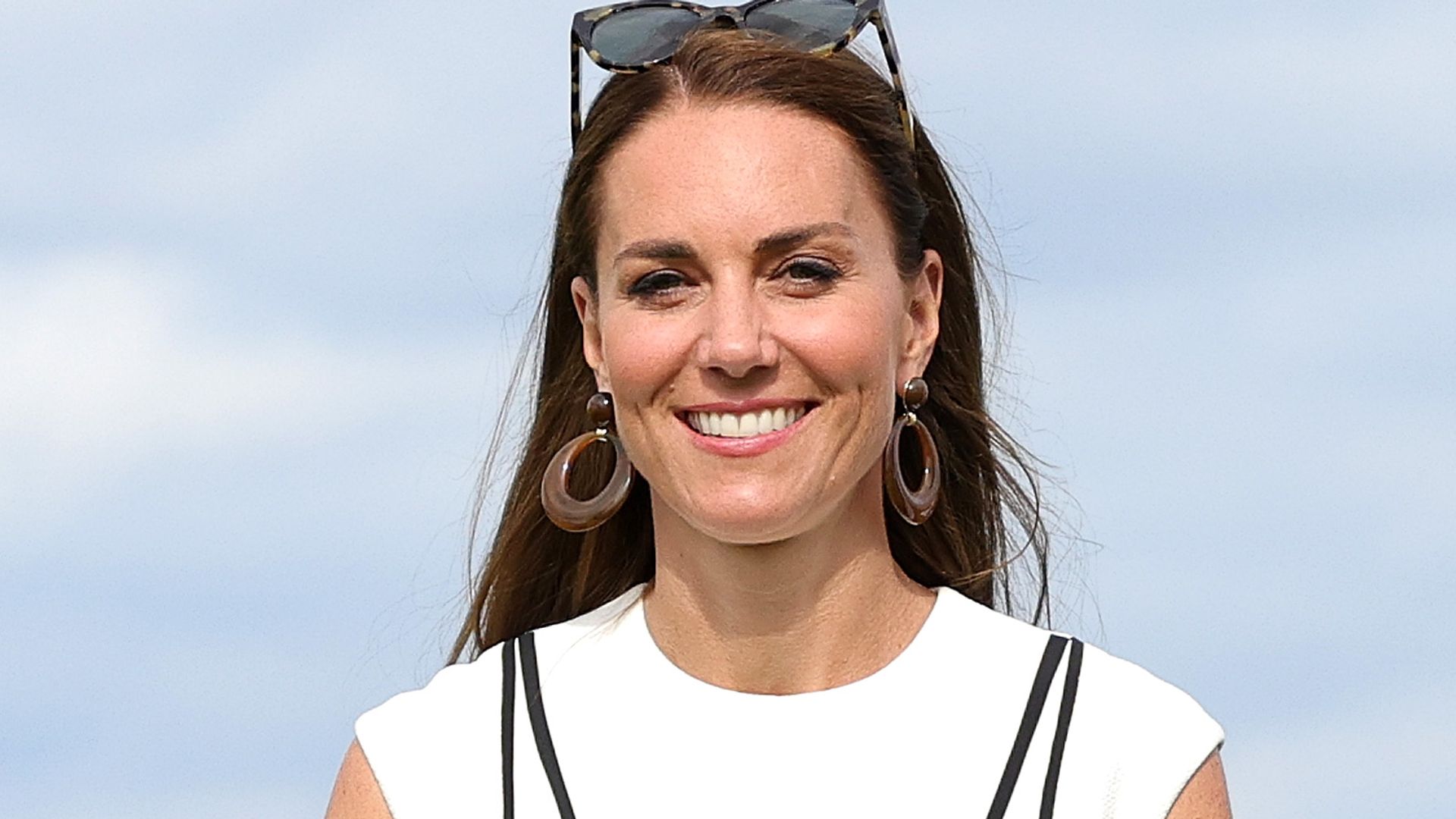 Princess Kate in a white dress with sunglasses on her head