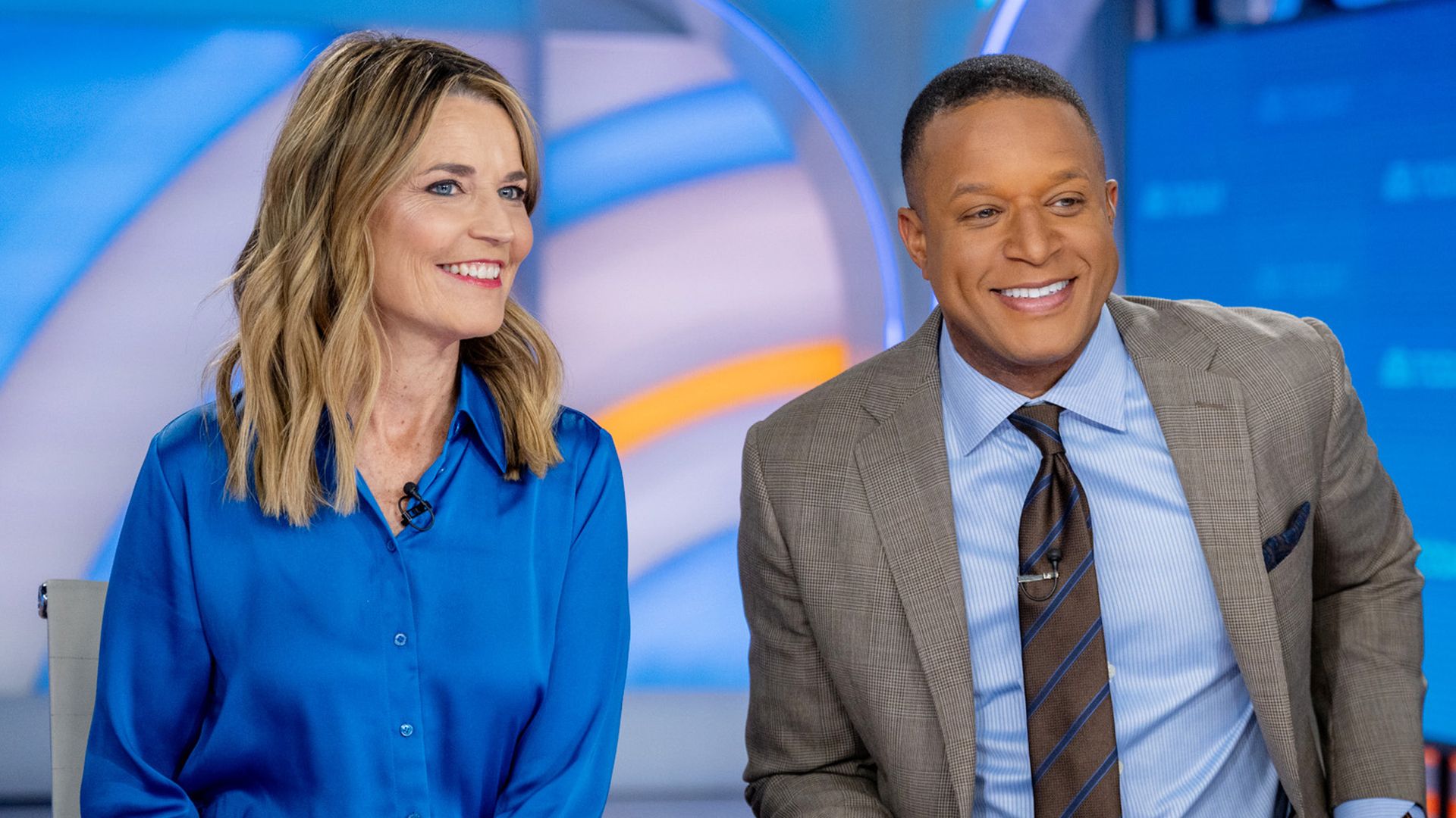 Female and male TV hosts sitting behind desk 