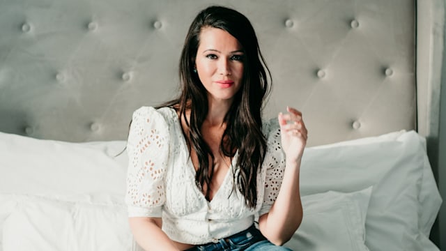 Beautiful brunette woman sitting on a bed