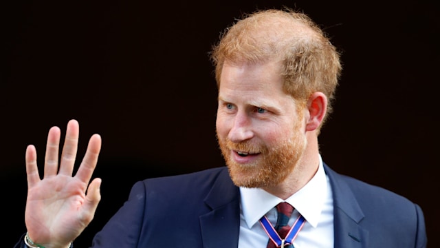 Prince Harry waving in a blue suit with medals