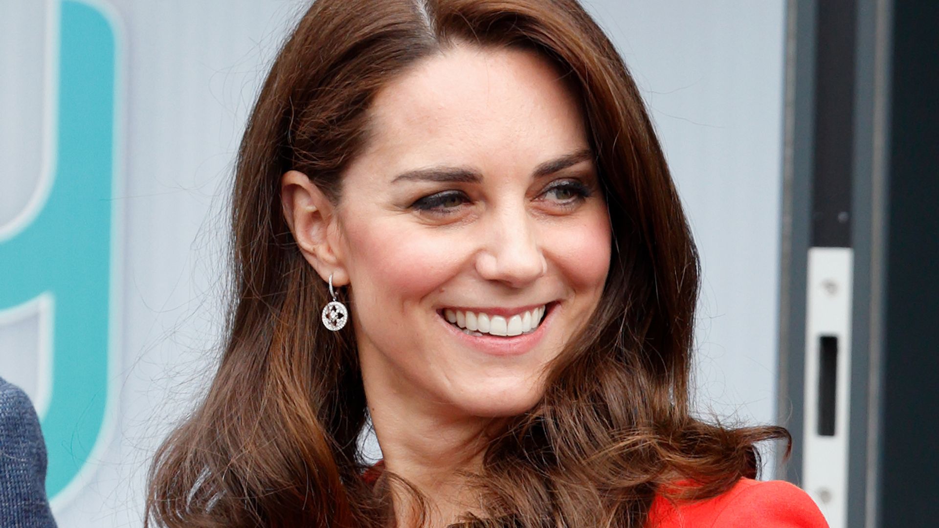 A close-up photo of Kate Middleton with Prince William and Prince Harry wearing red 