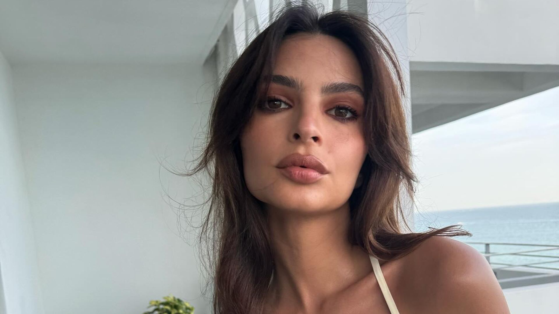 Emily Ratajkowski poses in a butter yellow dress on holiday