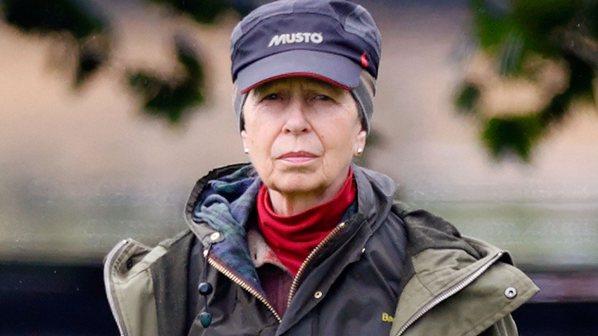 Princess Anne in a waterproof jacket and cap outside