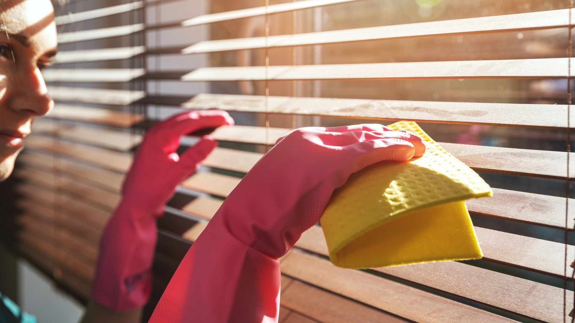 A woman cleaning blinds in her home