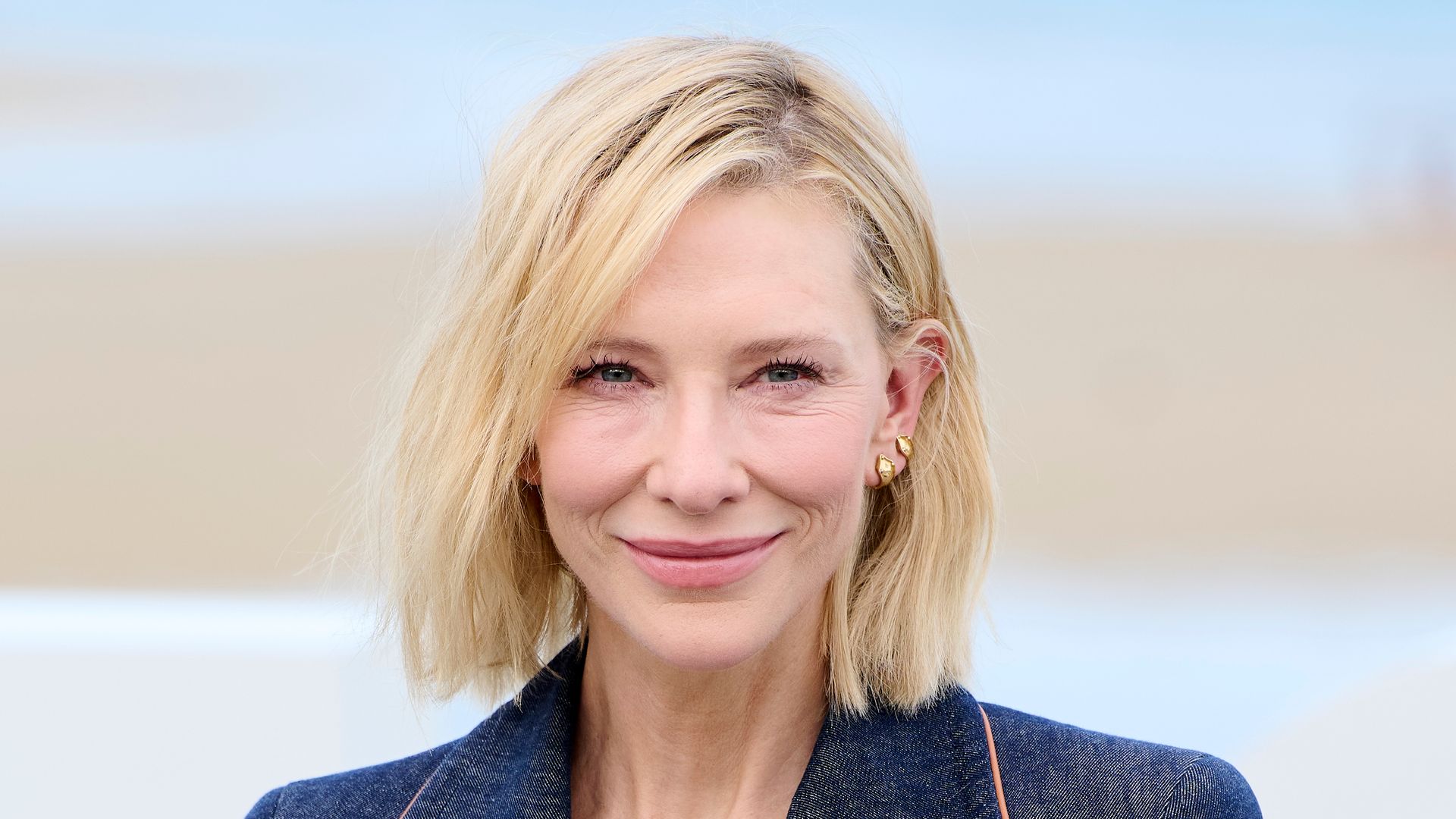 Cate Blanchett smiling in denim blazer shoulders up