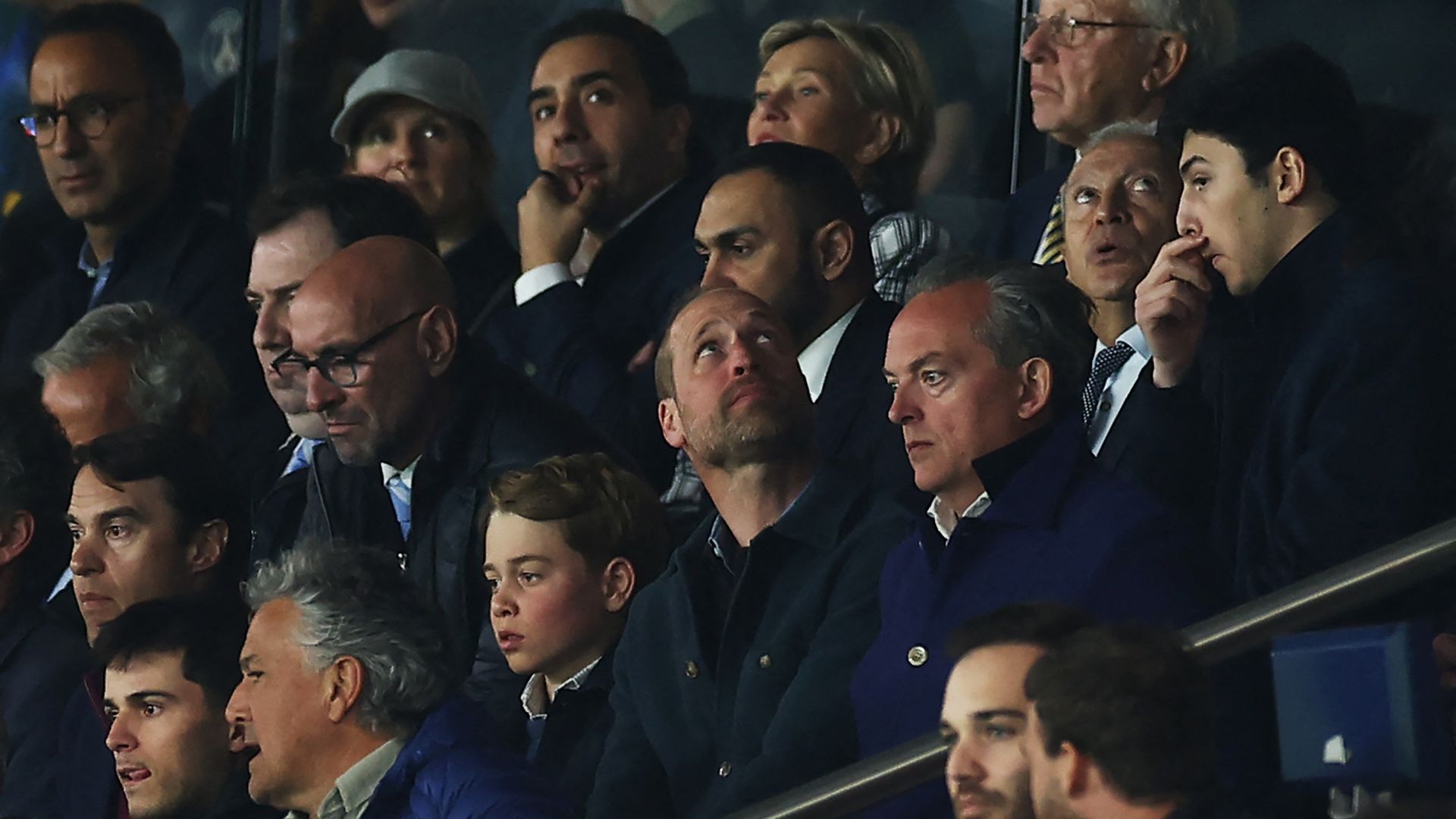 Prince George and Prince William looking unhappy at a football match