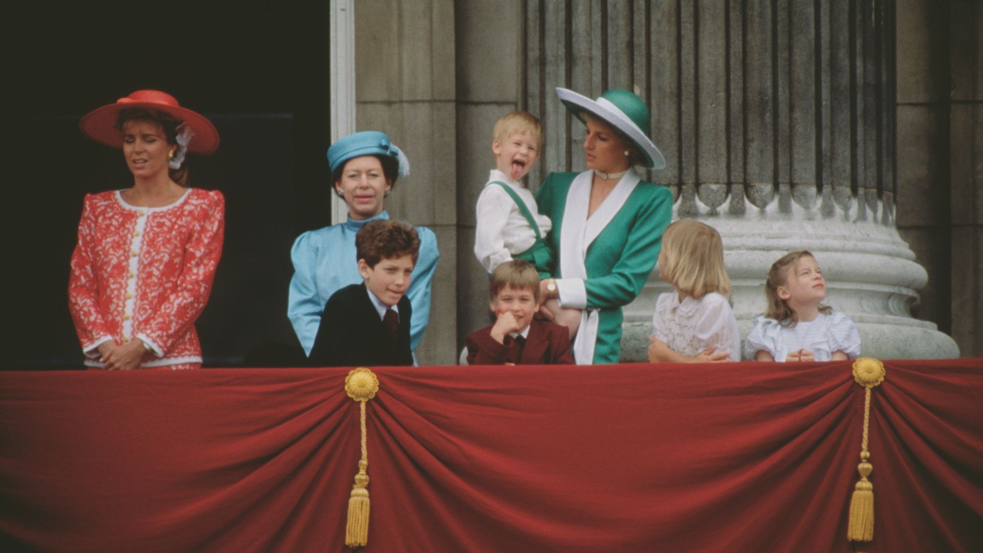 Princess Diana carrying Prince Harry as he pulls a face
