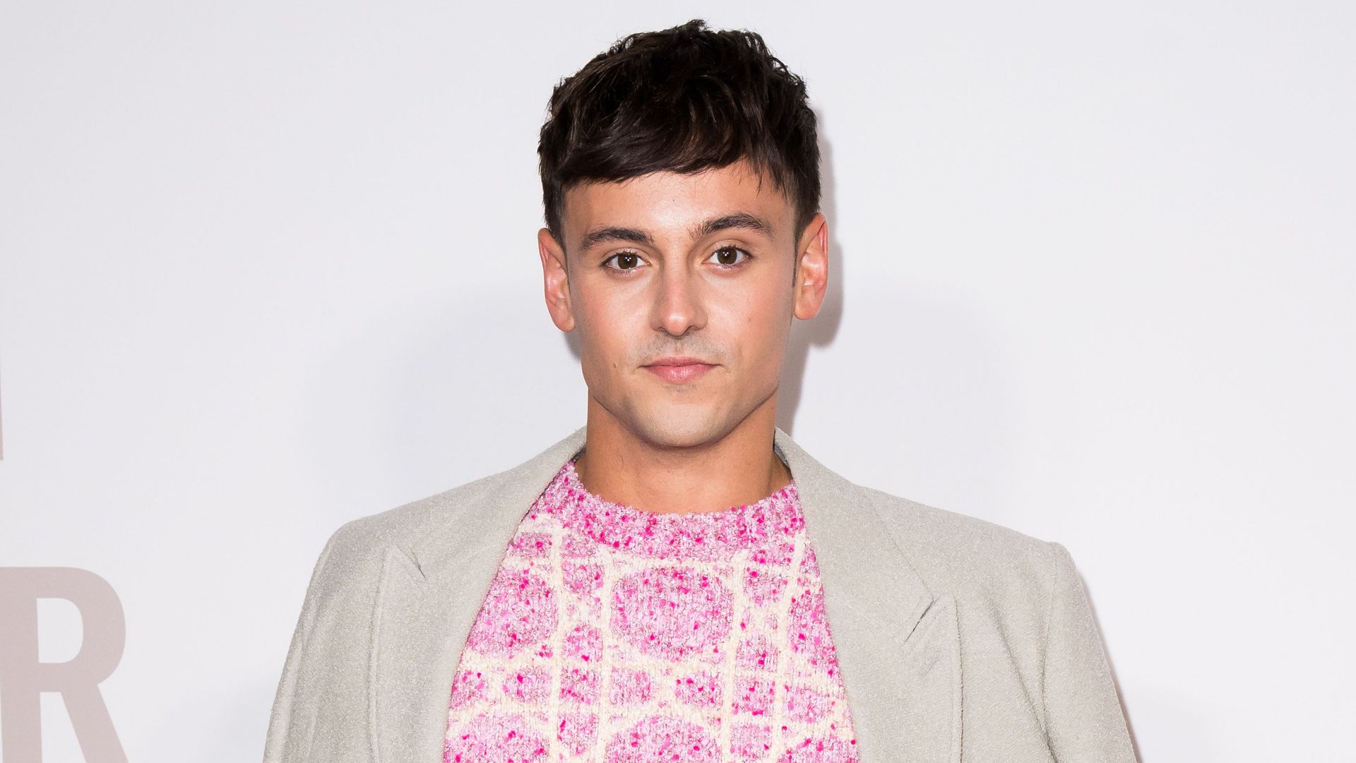 Tom Daley in a pink shirt and grey jacket