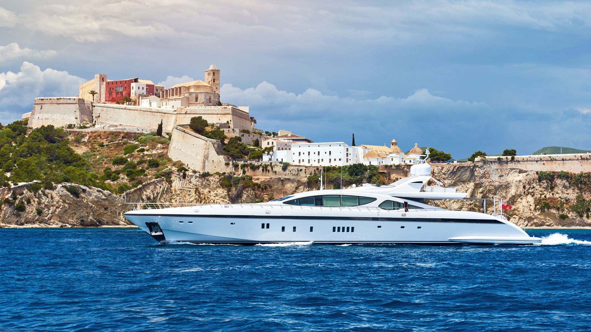 A yacht sailing past a cliffside town