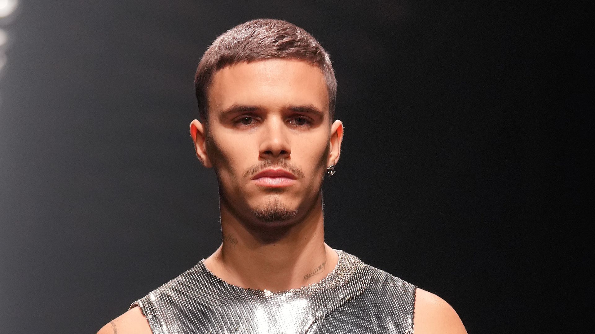 Romeo Beckham walking a runway in a grey tank top