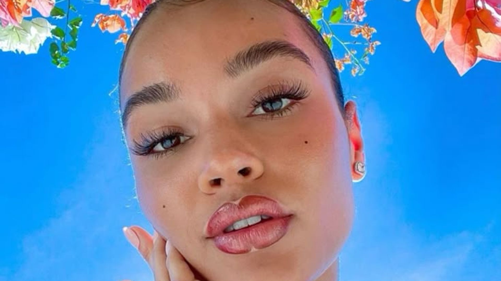 a woman with her hand on her face and flowers surrounding her 