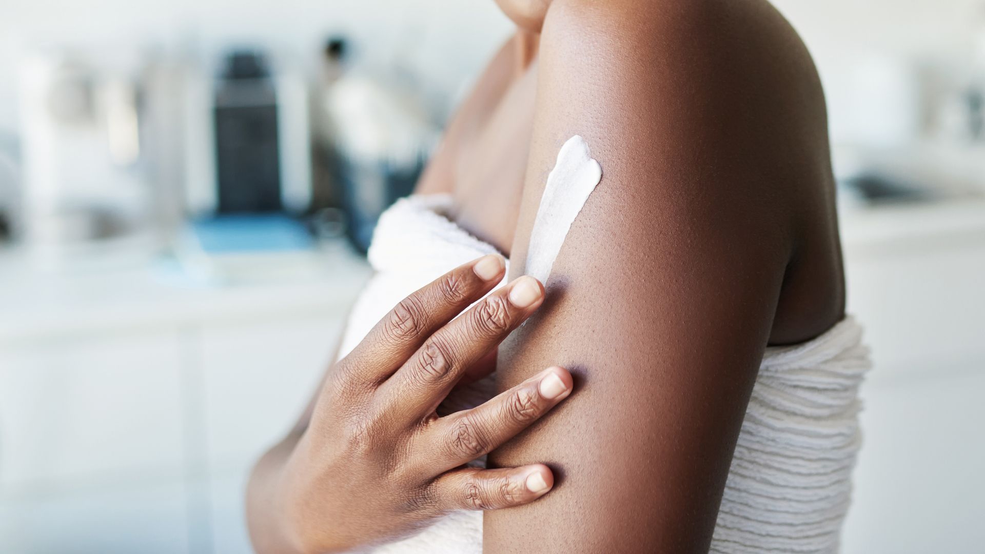 Cropped shot of a woman applying moisturiser to her body