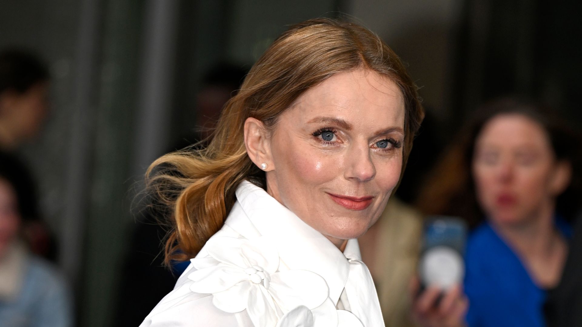 Geri Halliwell Horner in a ruffled while long sleeve dress looking over her shoulder