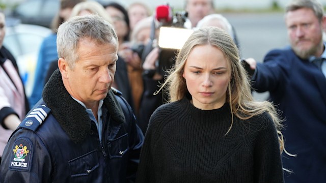 police officer escorting blonde woman away from crowd