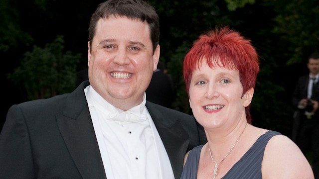 Peter Kay in a tailcoat with Susan Kay in a grey gown outside