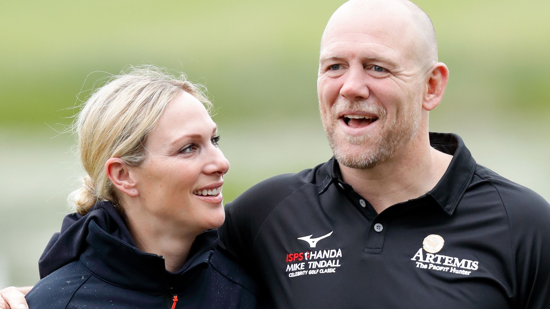 Zara Tindall in a jacket looking at Mike Tindall in a polo shirt and colourful trousers