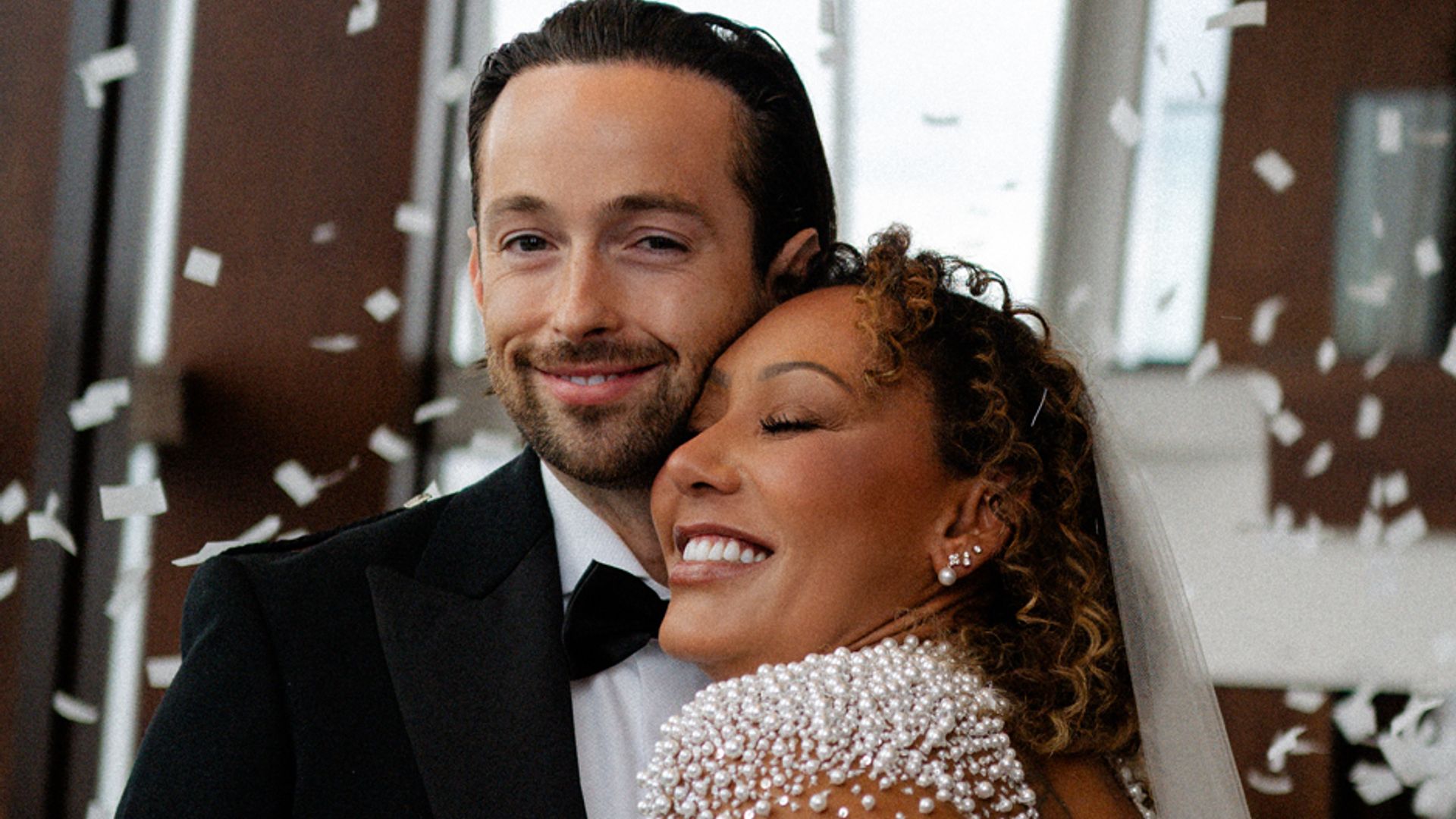 Mel B smiling and hugging her husband Rory while confetti is thrown over them