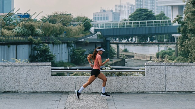 Female runner running across klang river in Kuala Lumpur City