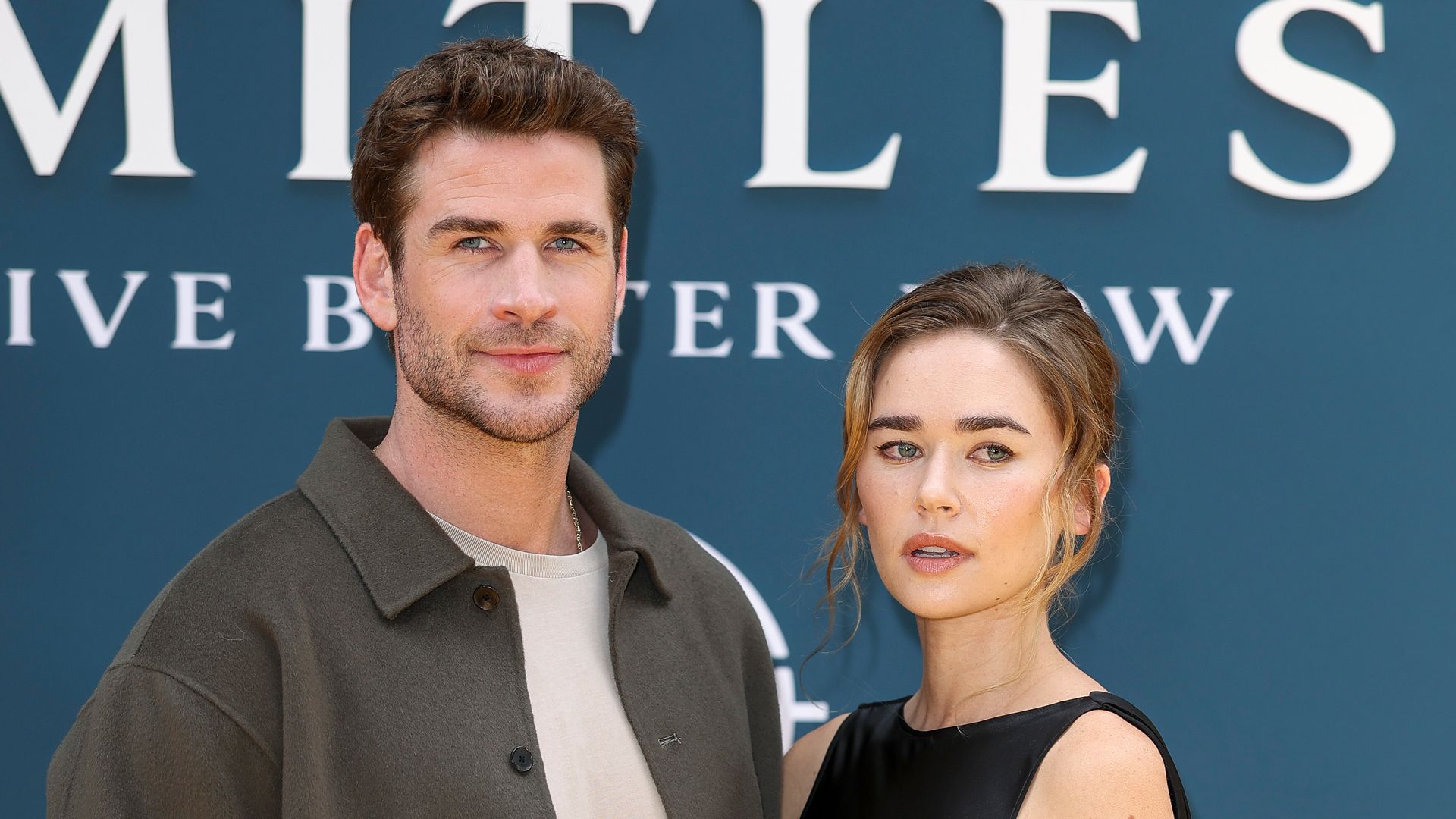 Liam Hemsworth in green shirt and Gabriella Brooks in black dress at the "Limitless: Live Better Now" UK Premiere at Odeon Luxe Leicester Square