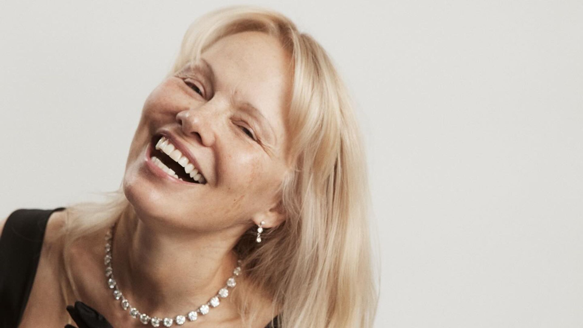 Pamela Anderson wearing a black dress and no makeup