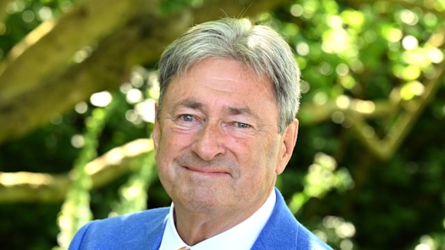 man posing in blue suit in garden