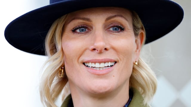 Zara Tindall smiling in a green jacket and blue hat