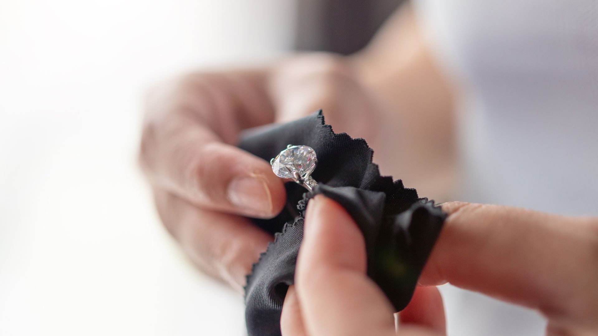 A person polishing a silver ring