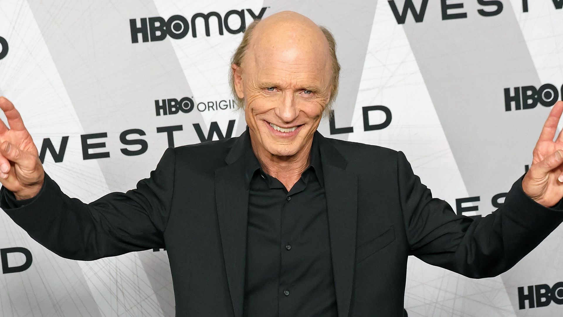 Ed Harris smiling and doing peace signs on a red carpet