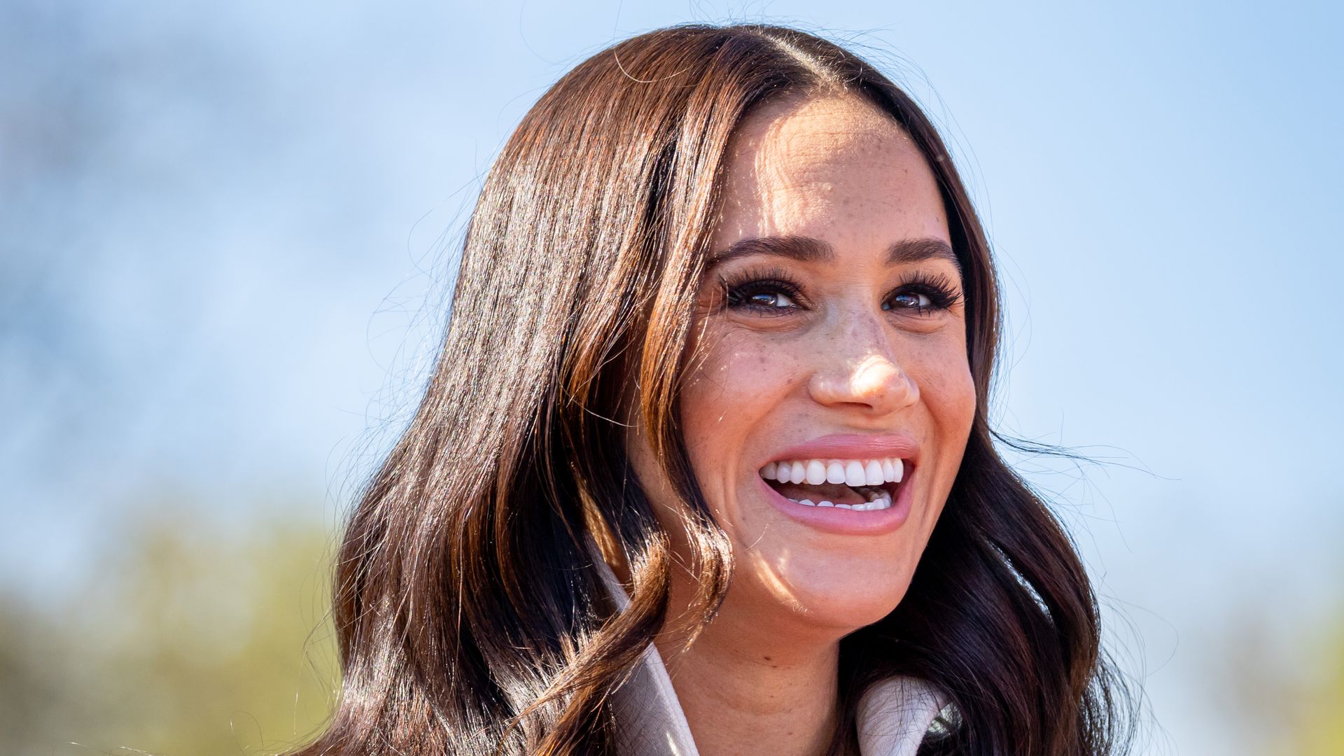 Meghan, Duchess of Sussex smiling in white jacket