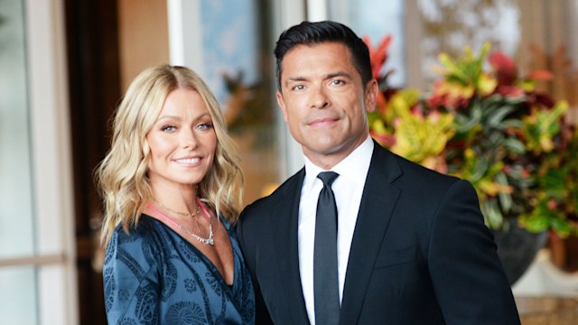 kelly ripa posing with mark consuelos in front of flowers