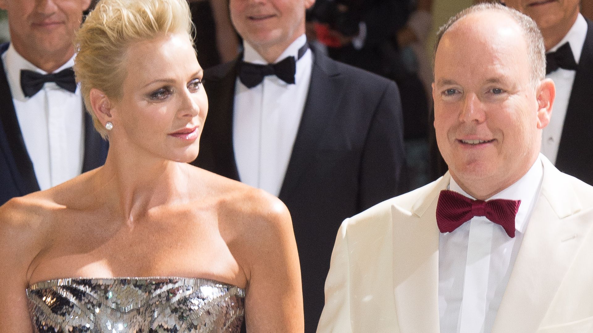 Princess Charlene in a silver strapless jumpsuit looking at her husband Prince Albert
