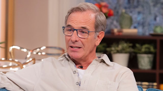 man in glasses sitting on blue sofa in tv studio