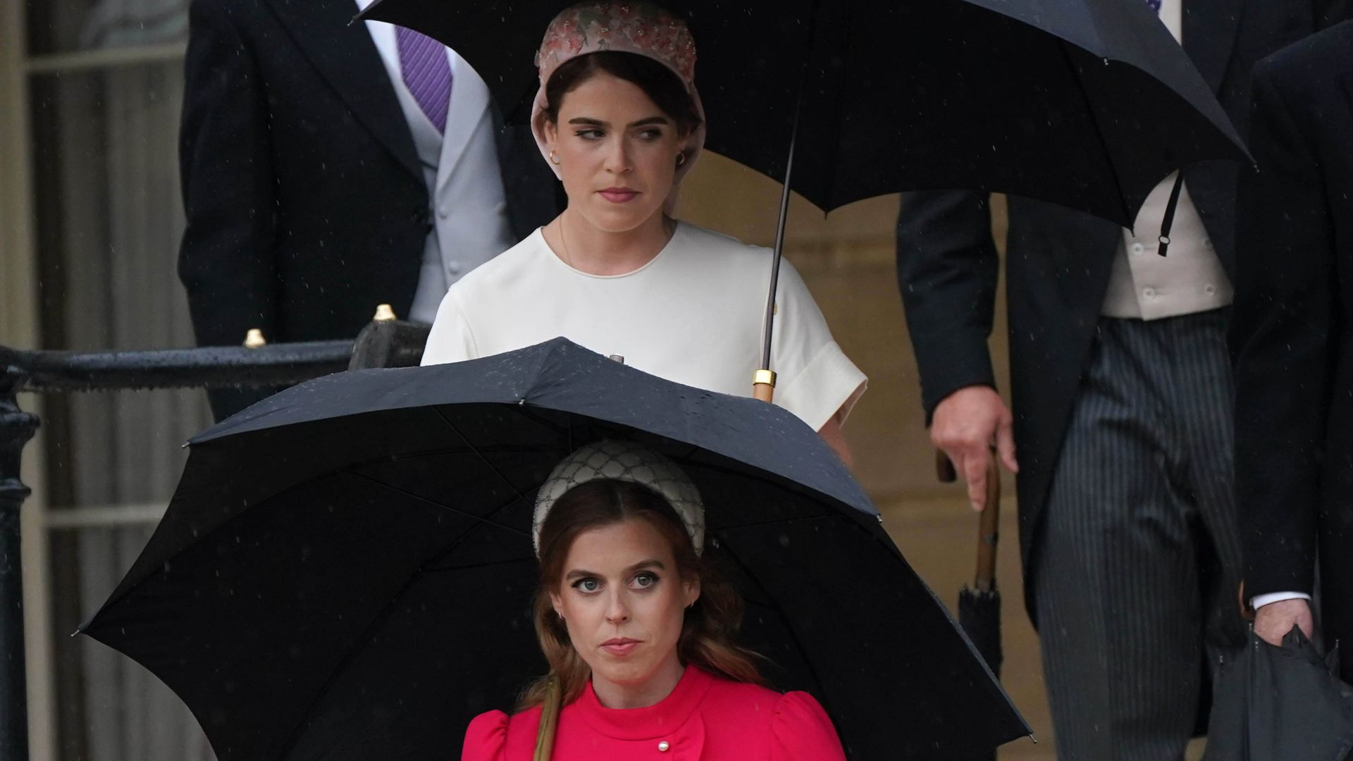 Princess Beatrice and Princess Eugenie holding umbrellas