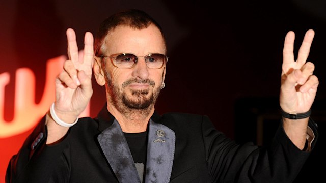 ringo star in glasses with both hands in peace sign position 