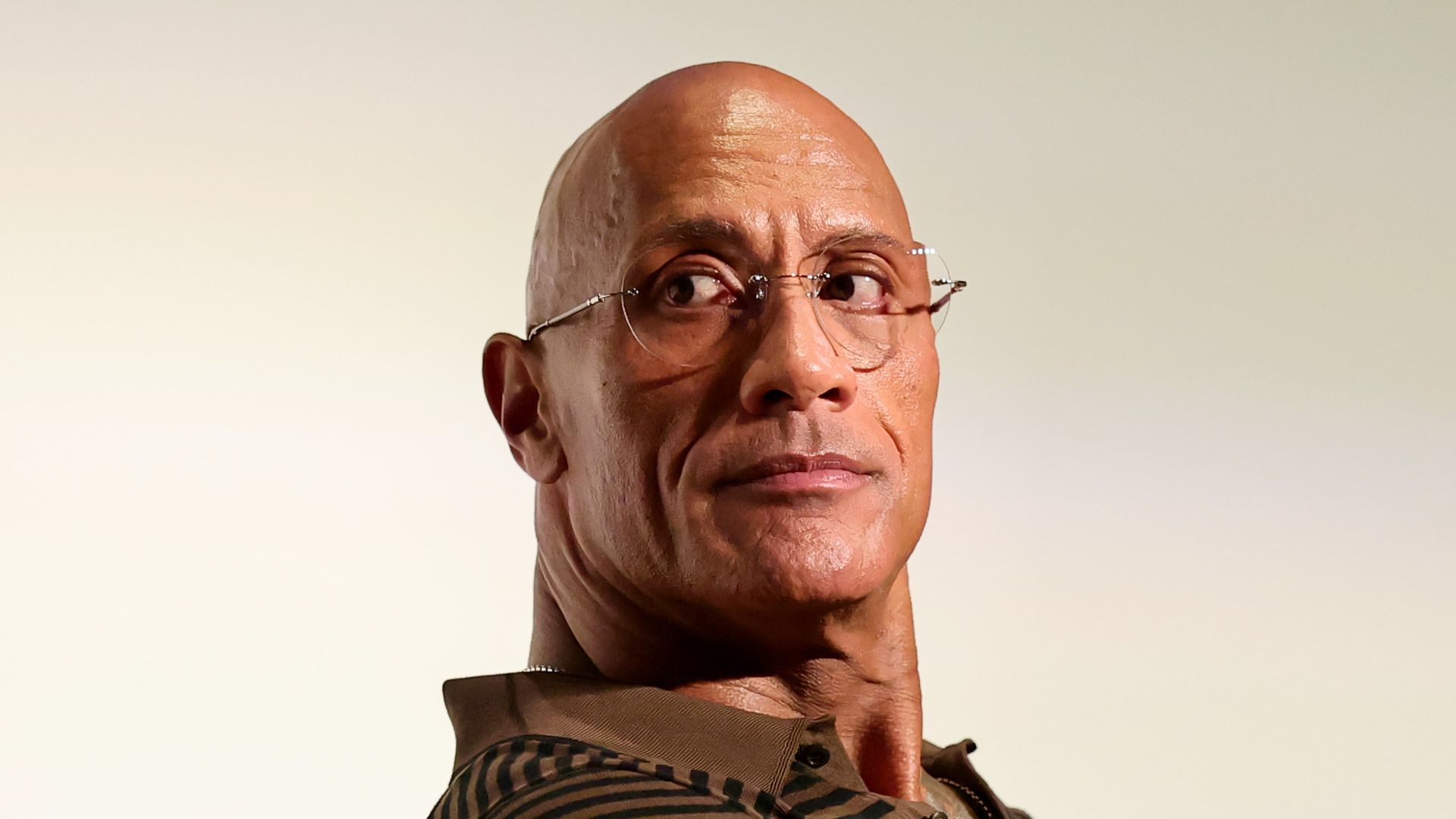 photo of dwayne johnson sitting on chair wearing glasses
