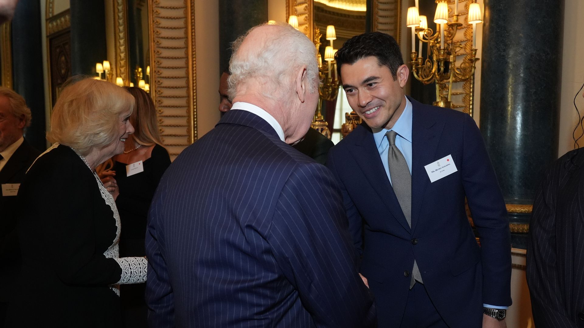 King Charles shaking hands with Henry Golding