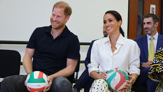 Prince Harry and Meghan sitting holding basketballs