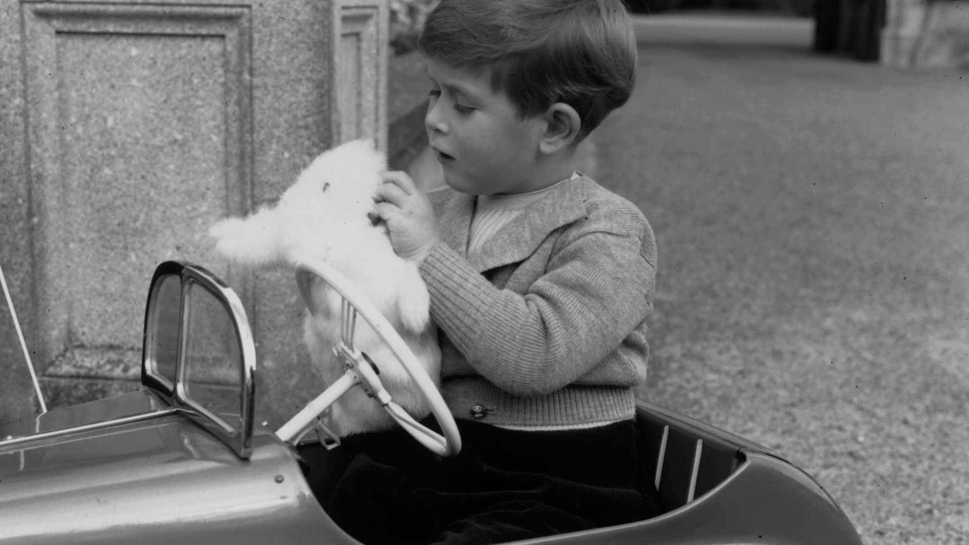 King Charles, eldest son of Queen Elizabeth II and the Duke of Edinburgh, playing with a glove puppet in his toy car whilst staying at Balmoral 