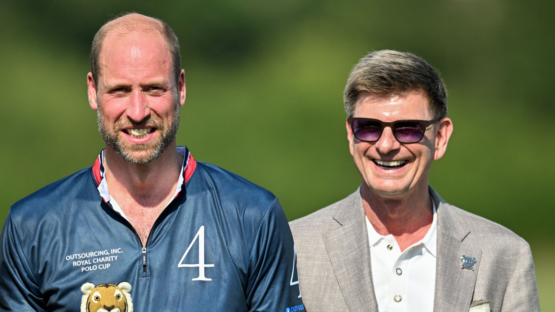 Prince William holding a tiger trophy alongside the CEO of Outsourcing International